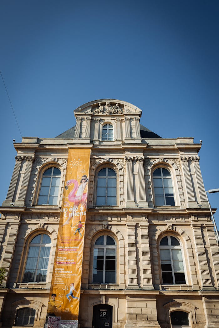 about-us-01 A detailed view of a historic building in Amiens, France, featuring a colorful event banner.