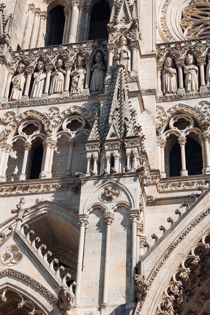 about-us-02 Close-up of the intricate Gothic facade of Amiens Cathedral showcasing detailed sculptures and architecture.